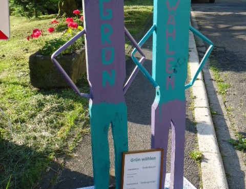 Foto von zwei Holz-Figuren mit der Aufschrift GRÜN Wählen